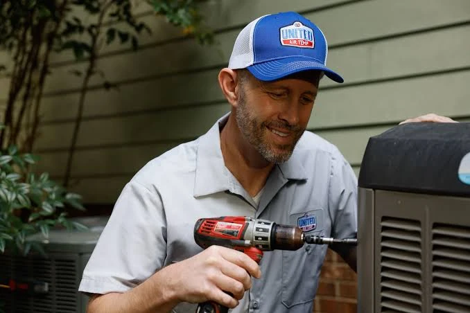 Technician using a cordless drill to service an outdoor air conditioning unit