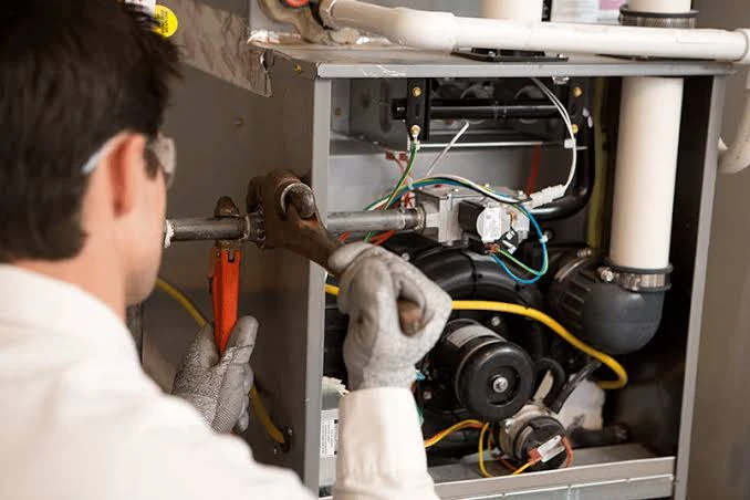 Technician inspecting internal furnace components and piping